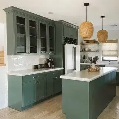 Modern kitchen with sage green cabinets, white countertops, island, and woven pendant lights.