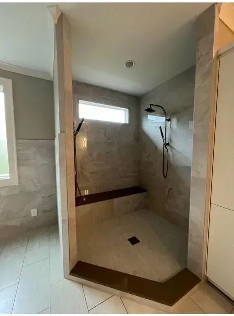 Walk-in shower with beige tile, white floor, and dual black showerheads in a bathroom