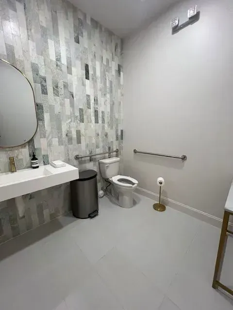 Modern bathroom with sink, toilet, wall-mounted mirror, and gray tile accent wall