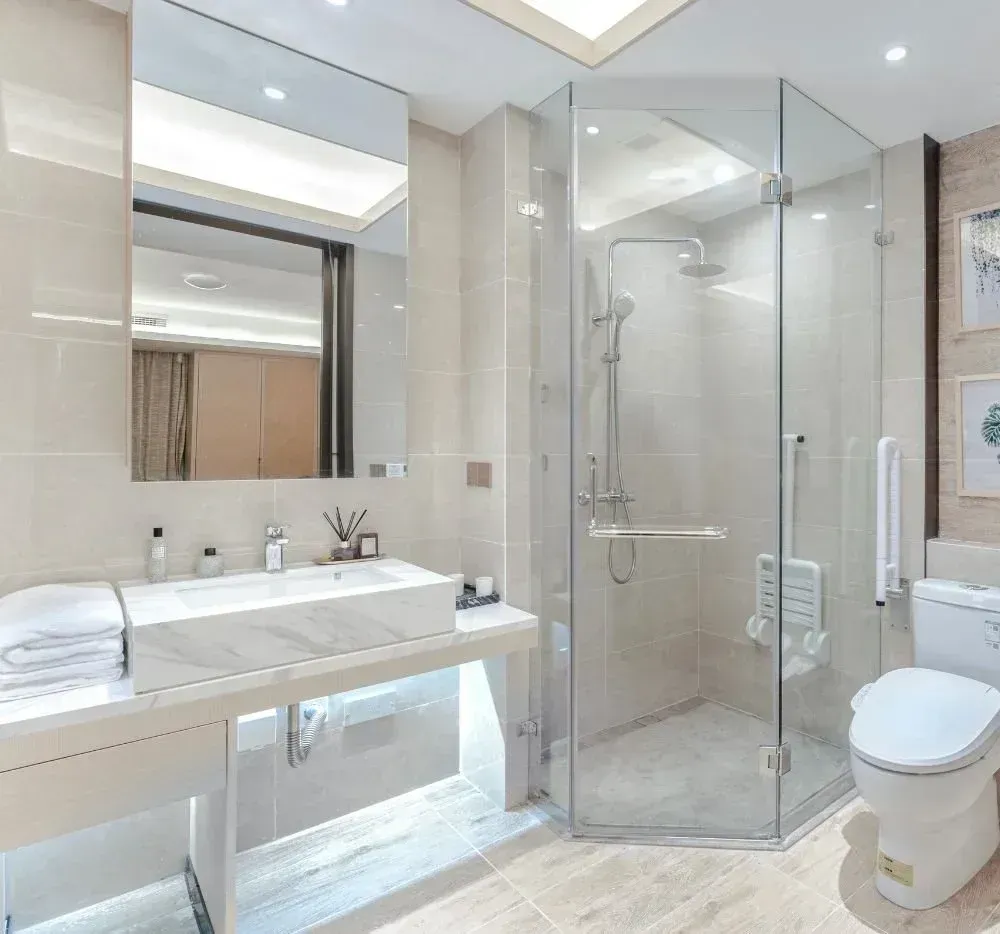 Modern white bathroom with glass shower, floating sink, mirror, and toilet