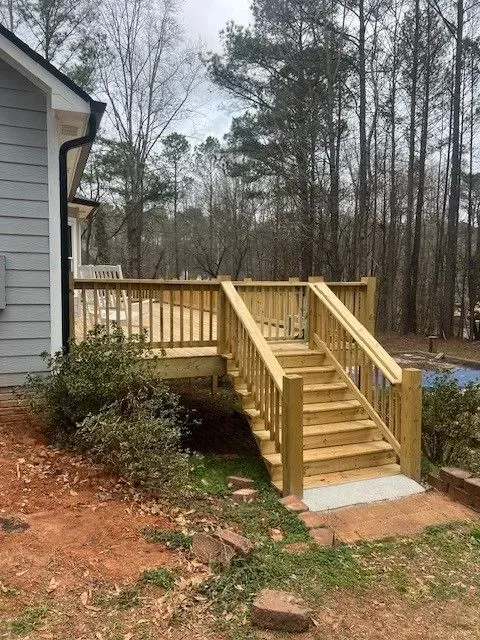 Wooden accessibility ramp and stairs beside a house in a wooded yard