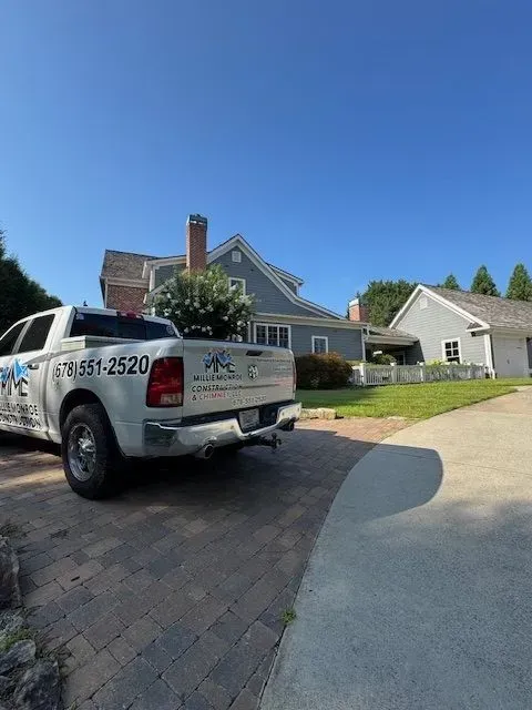 White pickup truck parked in a suburban driveway beside a house on a sunny day