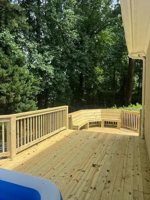 Wooden deck with railings overlooking dense green trees and a wooded backyard