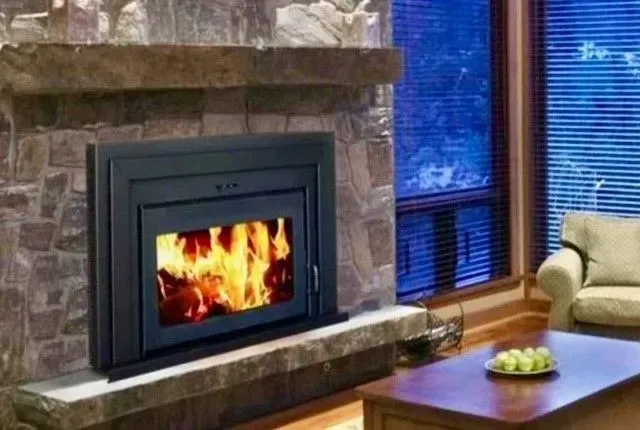 Stone fireplace with a bright fire in a cozy living room beside a window and sofa