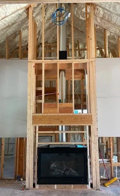 Framed fireplace wall under construction with exposed wood studs and unfinished drywall