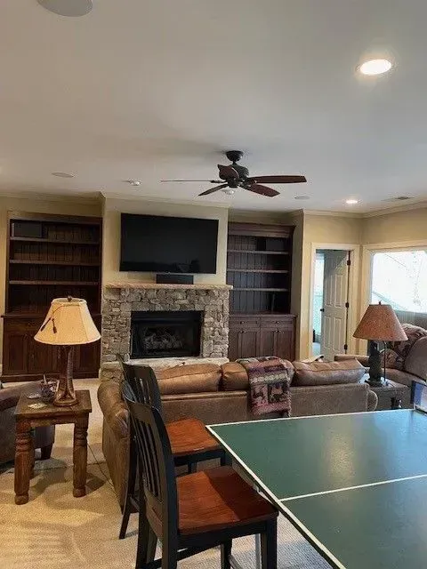 Living room with fireplace, built-in shelves, TV, sofa, and ping-pong table