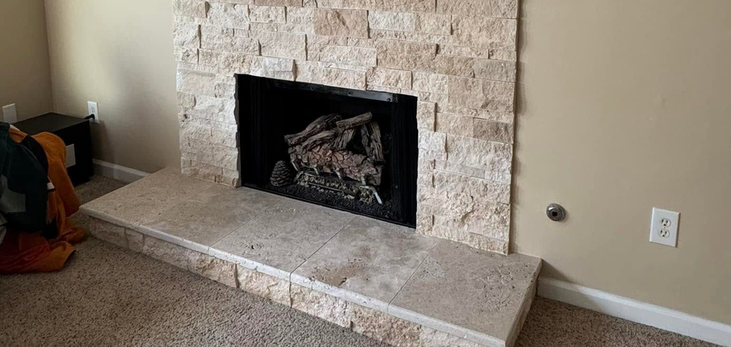 Stone fireplace with dark wood mantel and raised hearth in a beige living room.