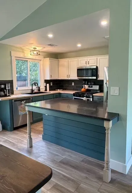 Bright kitchen with white cabinets, black countertops, island, and recessed lighting