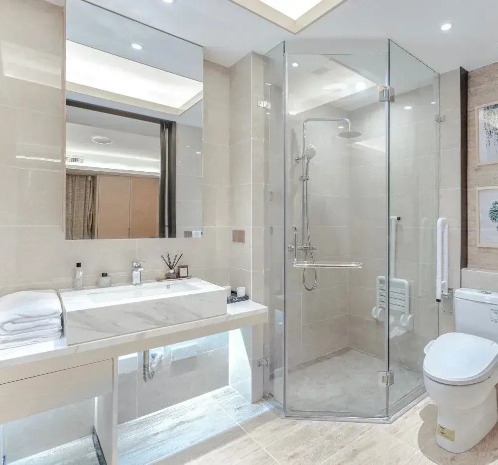 Modern white bathroom with vanity, glass shower enclosure, and toilet.