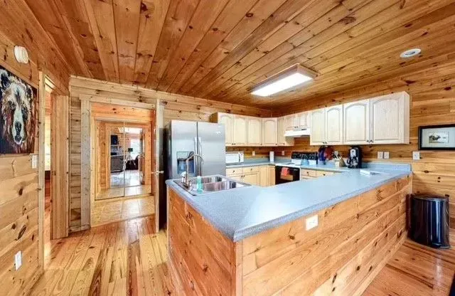 Wood-paneled kitchen with white cabinets, blue countertops, and stainless steel appliances