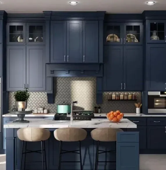 Modern navy kitchen with marble island, beige stools, and pendant lights under cabinets.
