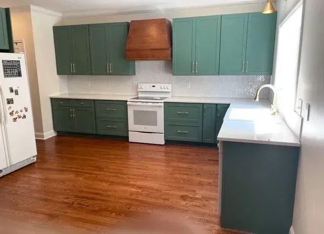 Kitchen with teal cabinets, white stove, wood range hood, and hardwood floor.
