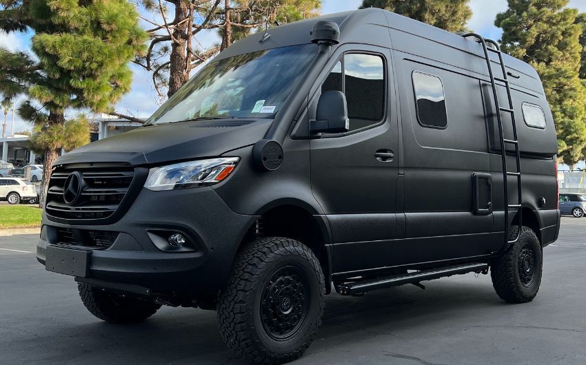 A black van with a ladder on the roof is parked on the side of the road.