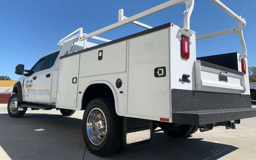 A white utility truck is parked in a parking lot.