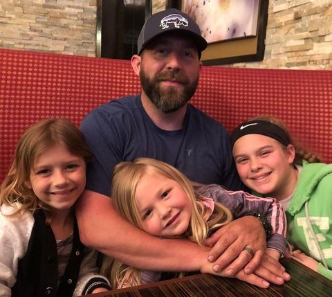 A man and three little girls are posing for a picture