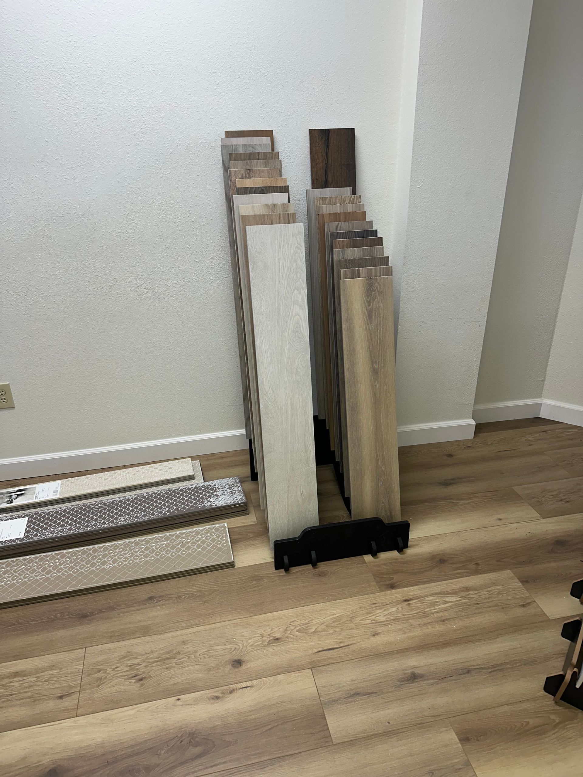 Flooring samples leaning against a white wall; wood flooring in the foreground.