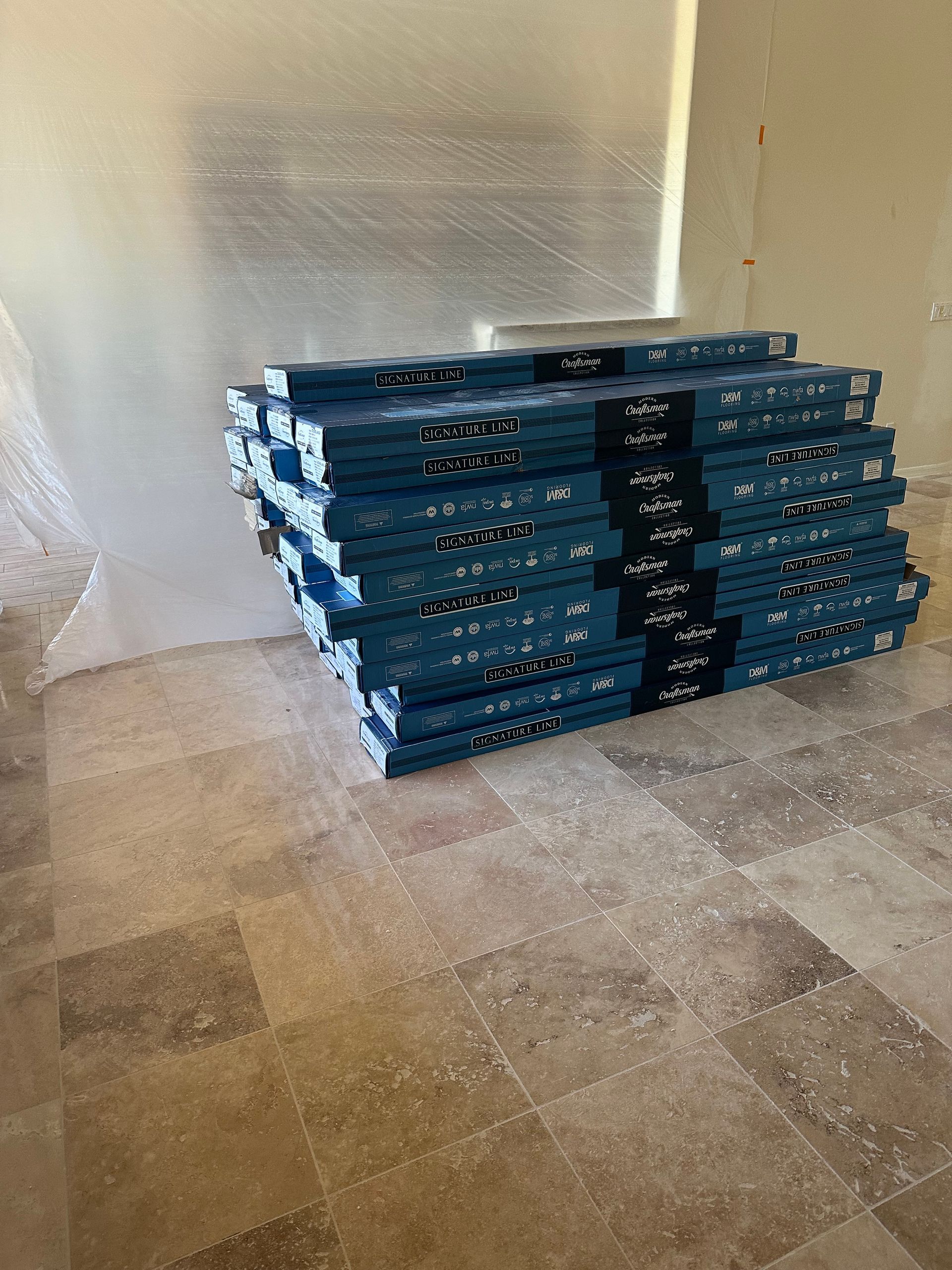 Stack of blue-wrapped flooring planks on a checkered floor in a room with translucent walls.