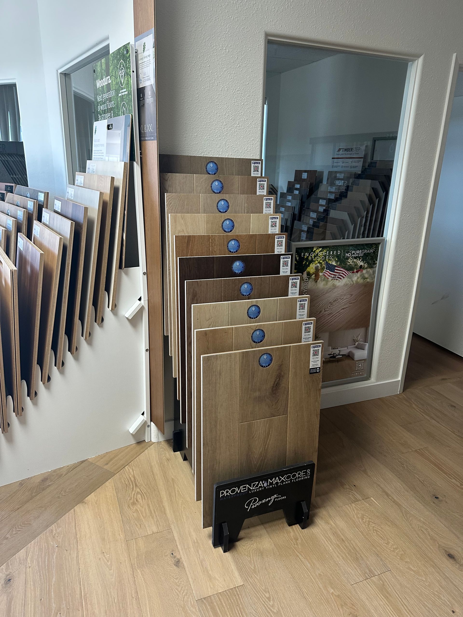 Flooring samples on display in a showroom; various wood tones and textures are visible.
