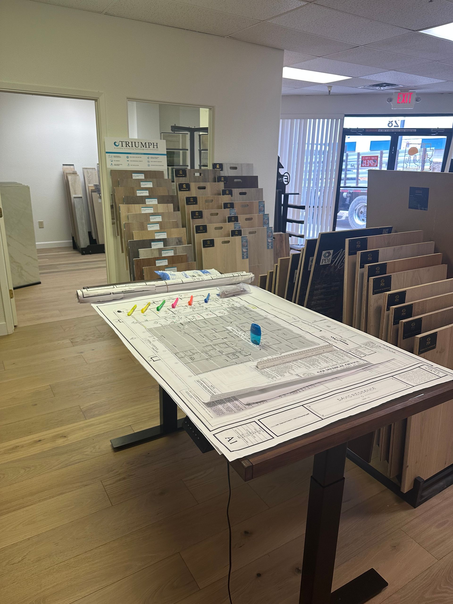 Interior of a tile store; drawing table in the foreground, tile samples in the background.