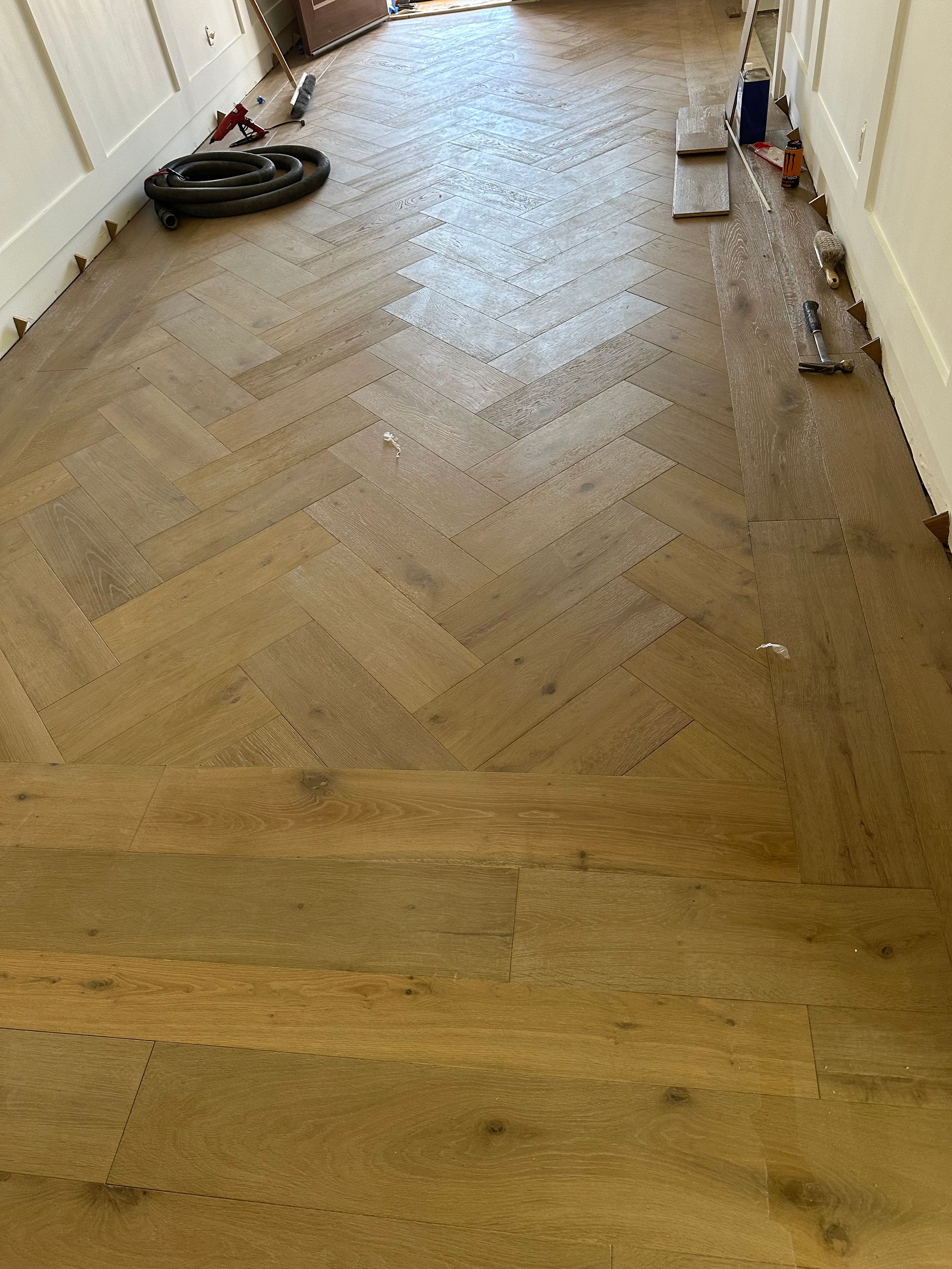 Herringbone wood floor installation in progress.