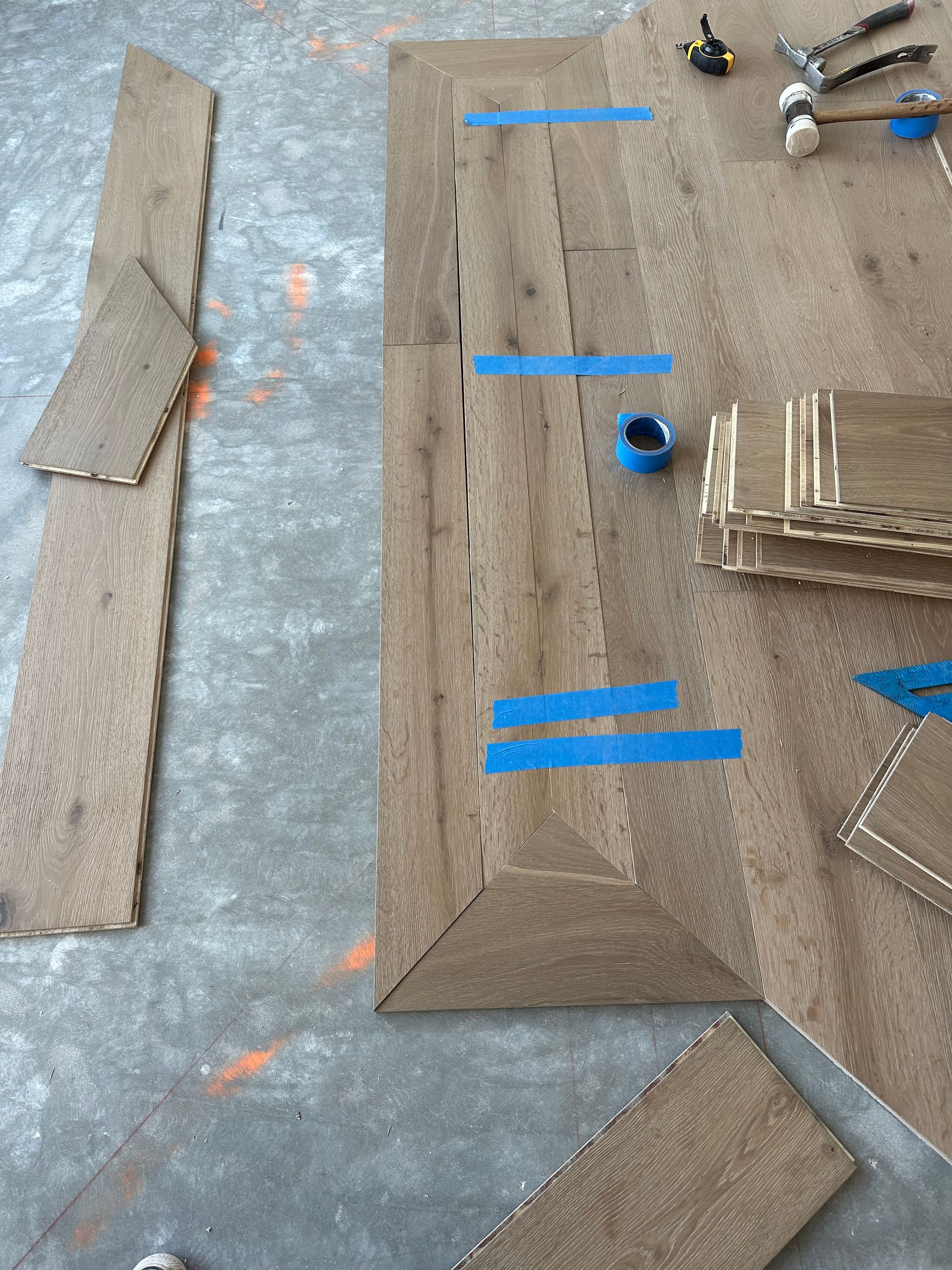 Construction: Close-up of wooden tiles, tape, and tools on a concrete floor.