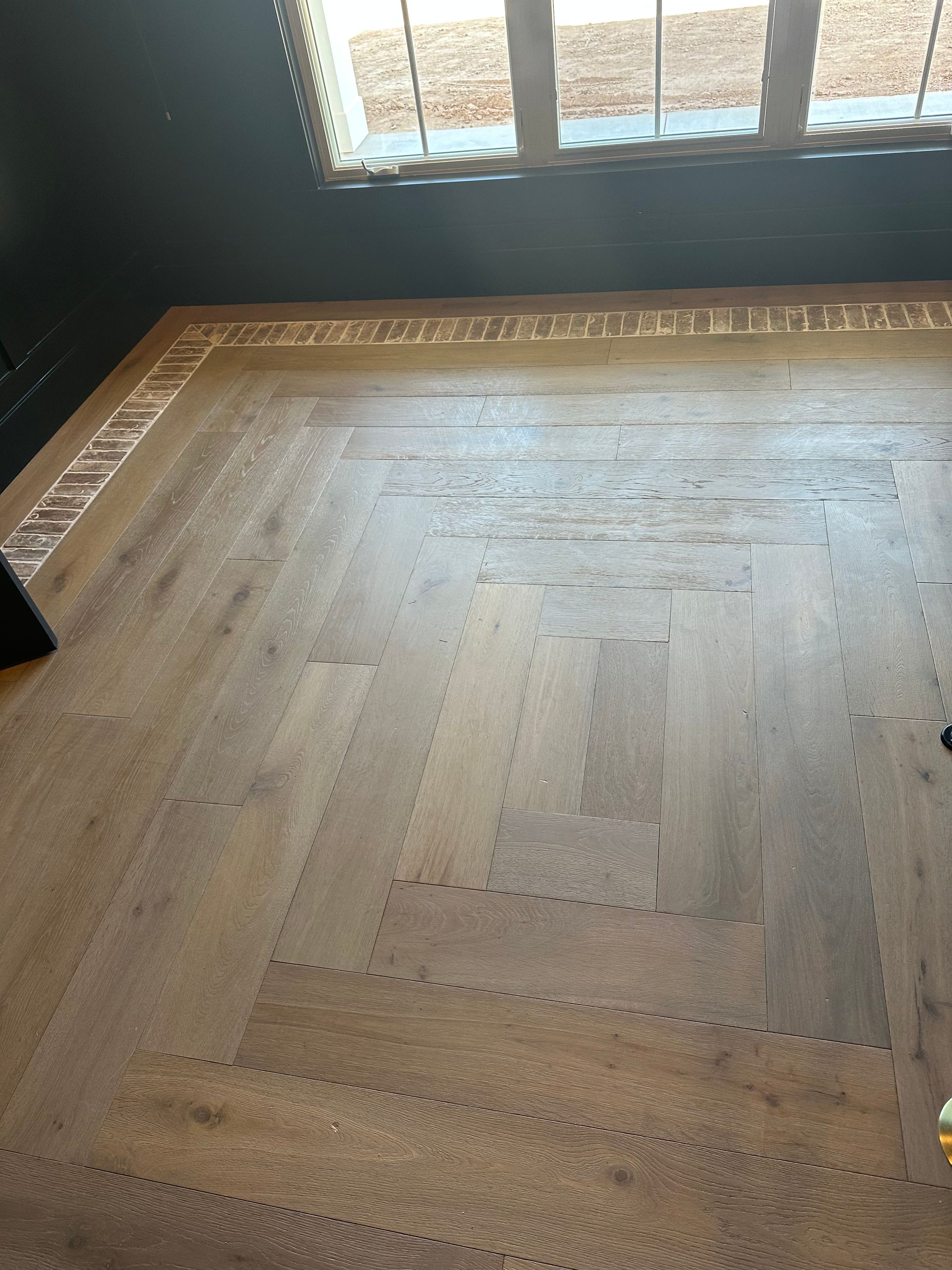 Wooden floor with a patterned border, next to a window.