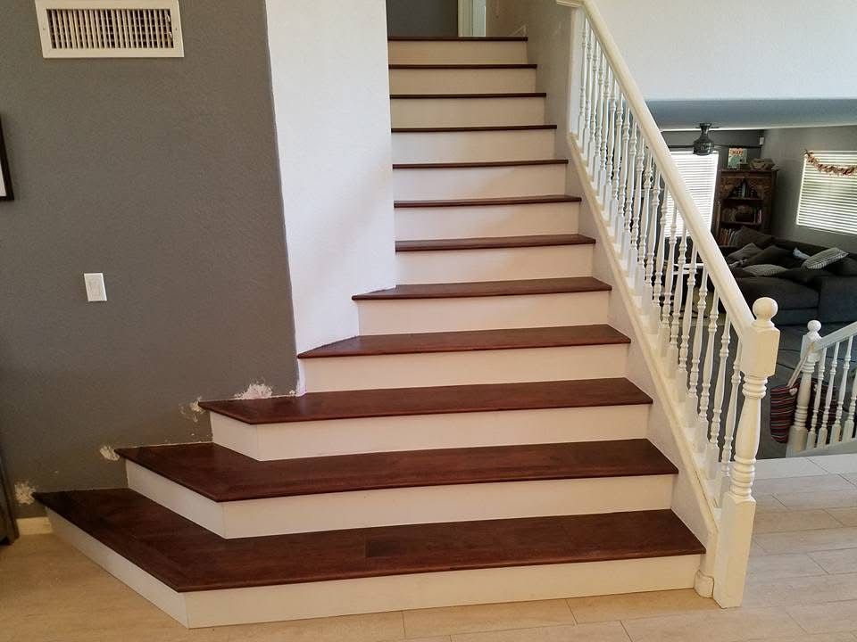 Wooden staircase with white risers and railing, leading to an upper level.