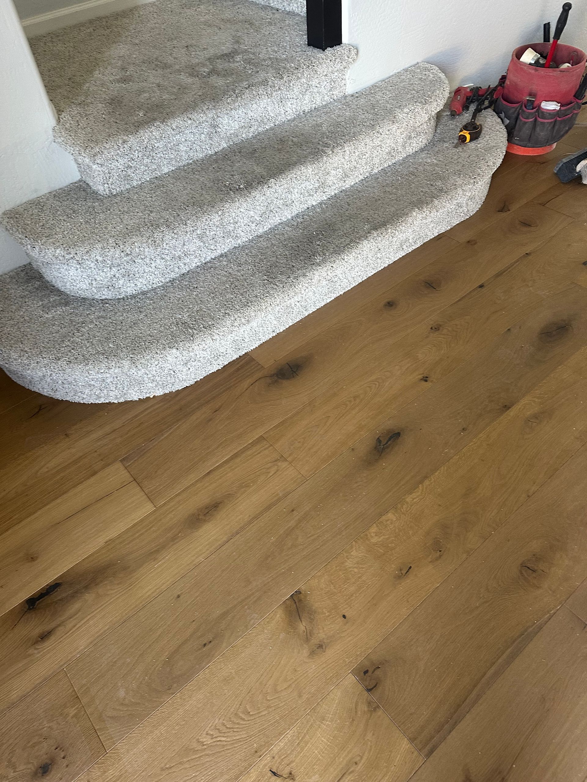 Wooden floor leads to carpeted staircase. Tools sit at the top of the stairs.