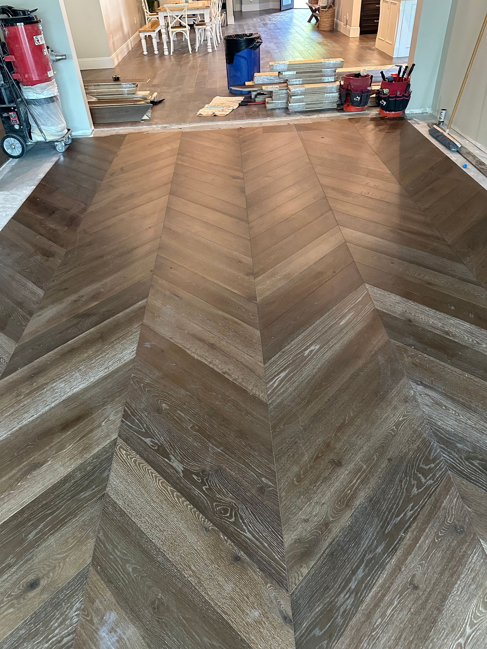 Herringbone pattern hardwood floor in a room; brown, white, and gray tones.