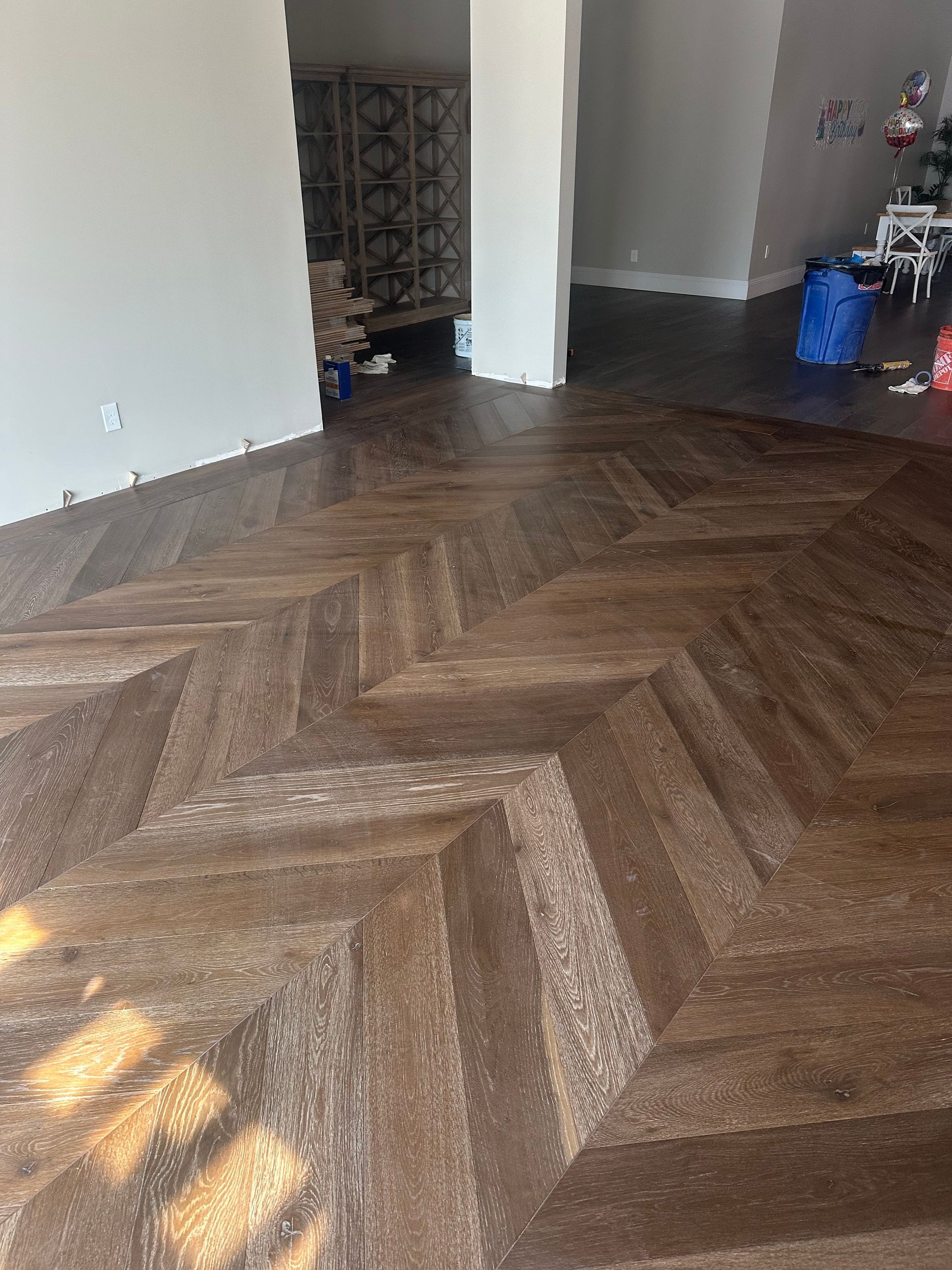 Herringbone patterned dark wood floor in a room with white walls.