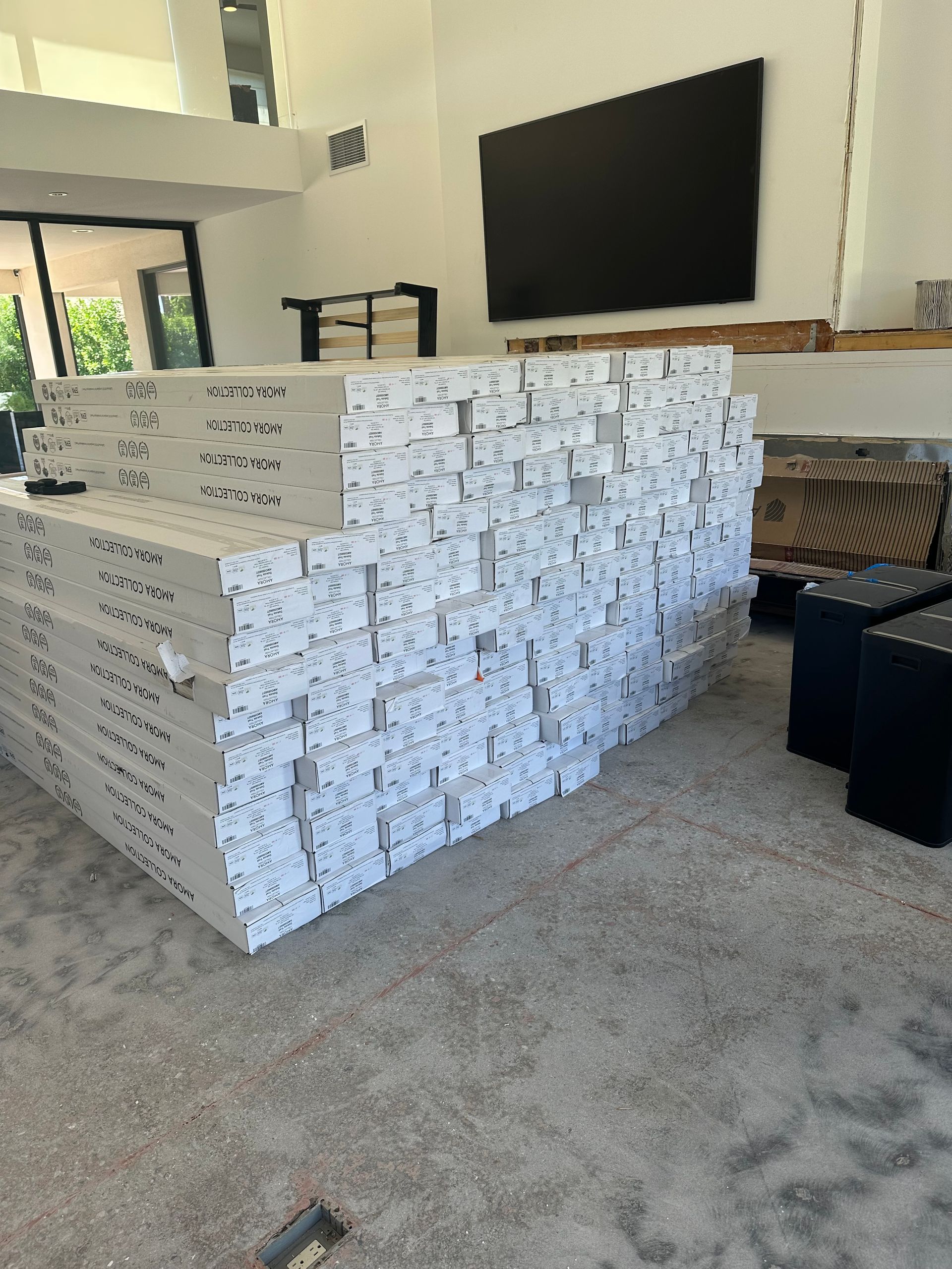 A pile of white boards in a room with a large screen, possibly under construction.
