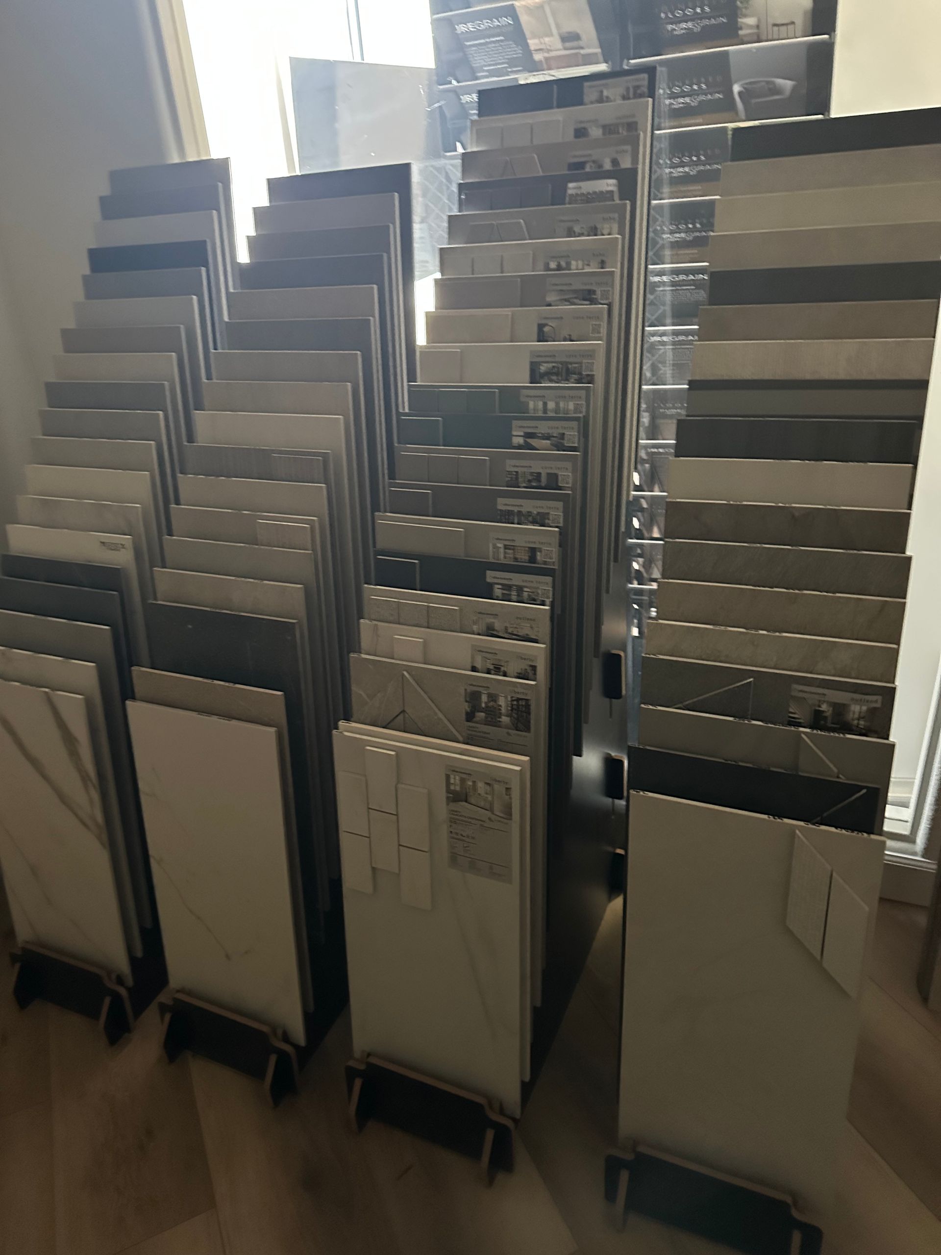 Tile samples displayed on racks in a showroom, showcasing various colors and patterns.