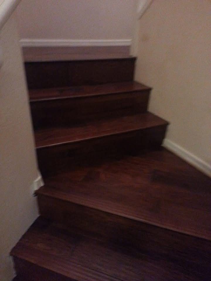 Dark wooden stairs leading upwards, against beige walls.
