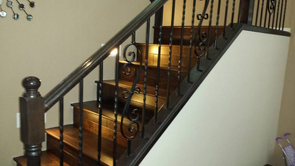 Wooden staircase with dark railing and decorative iron balusters.