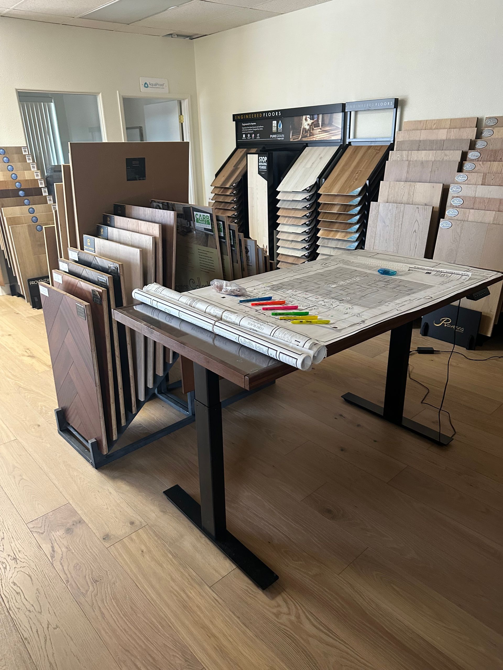 Interior shop with floor and wall samples on display, wooden table in foreground.