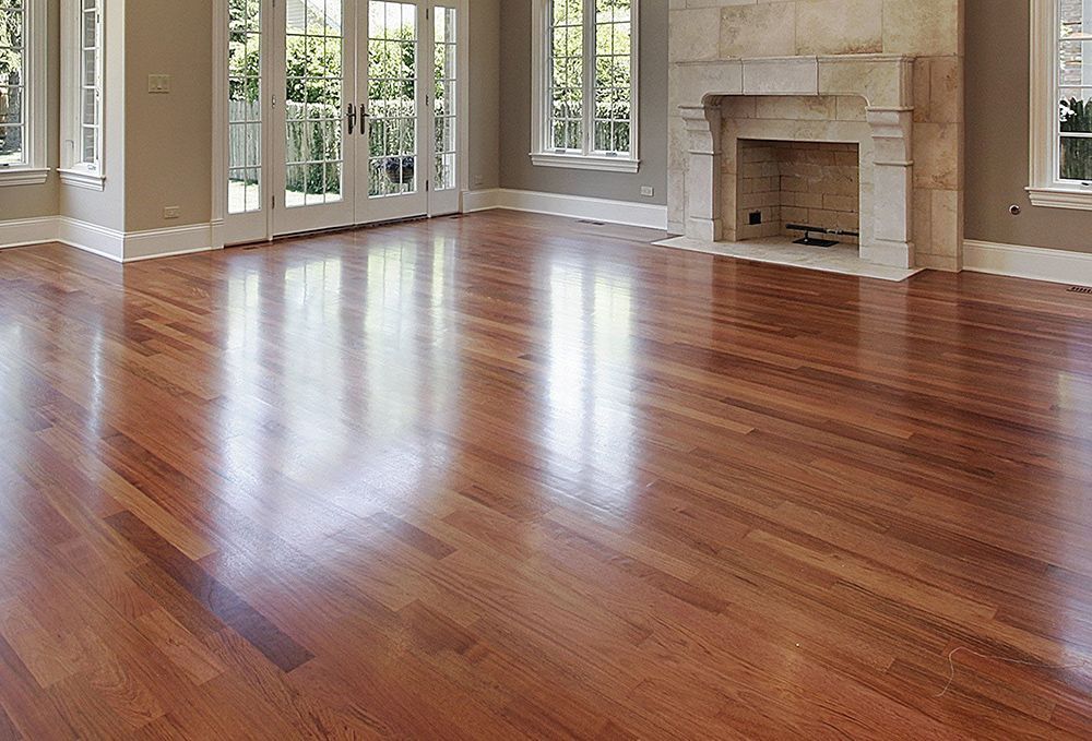 Shiny, polished hardwood floor in a well-lit room with a fireplace and windows.