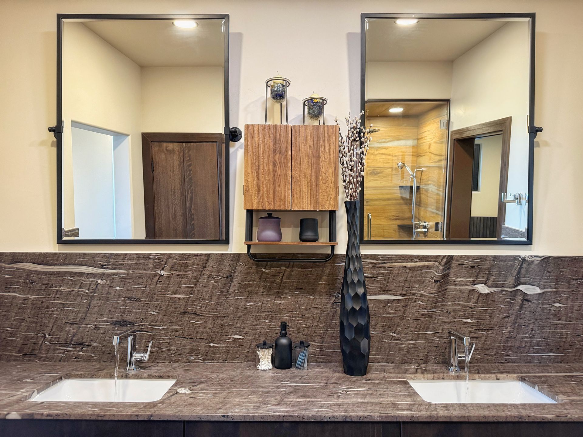 Bathroom vanity with two sinks, large mirrors, and a wooden cabinet centered between them