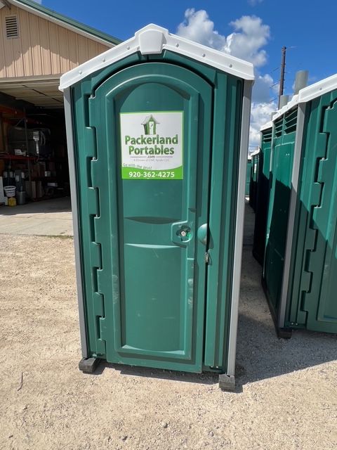 A row of green portable toilets in a gray parking lot, snowy and overcast.