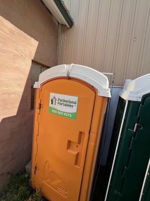 Gray portable toilet with Packerland Portables logo and ADA symbol.