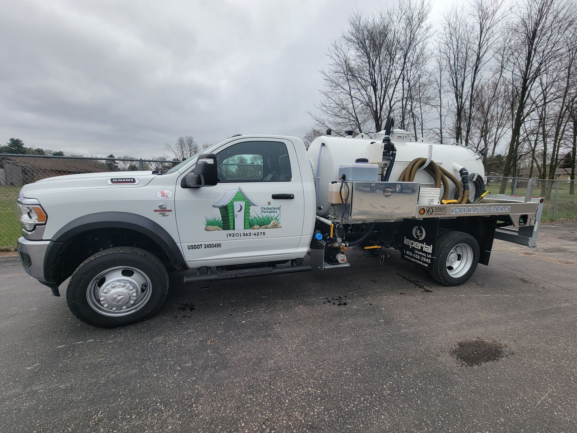 Group of people standing on a trailer in front of a red and gray building.