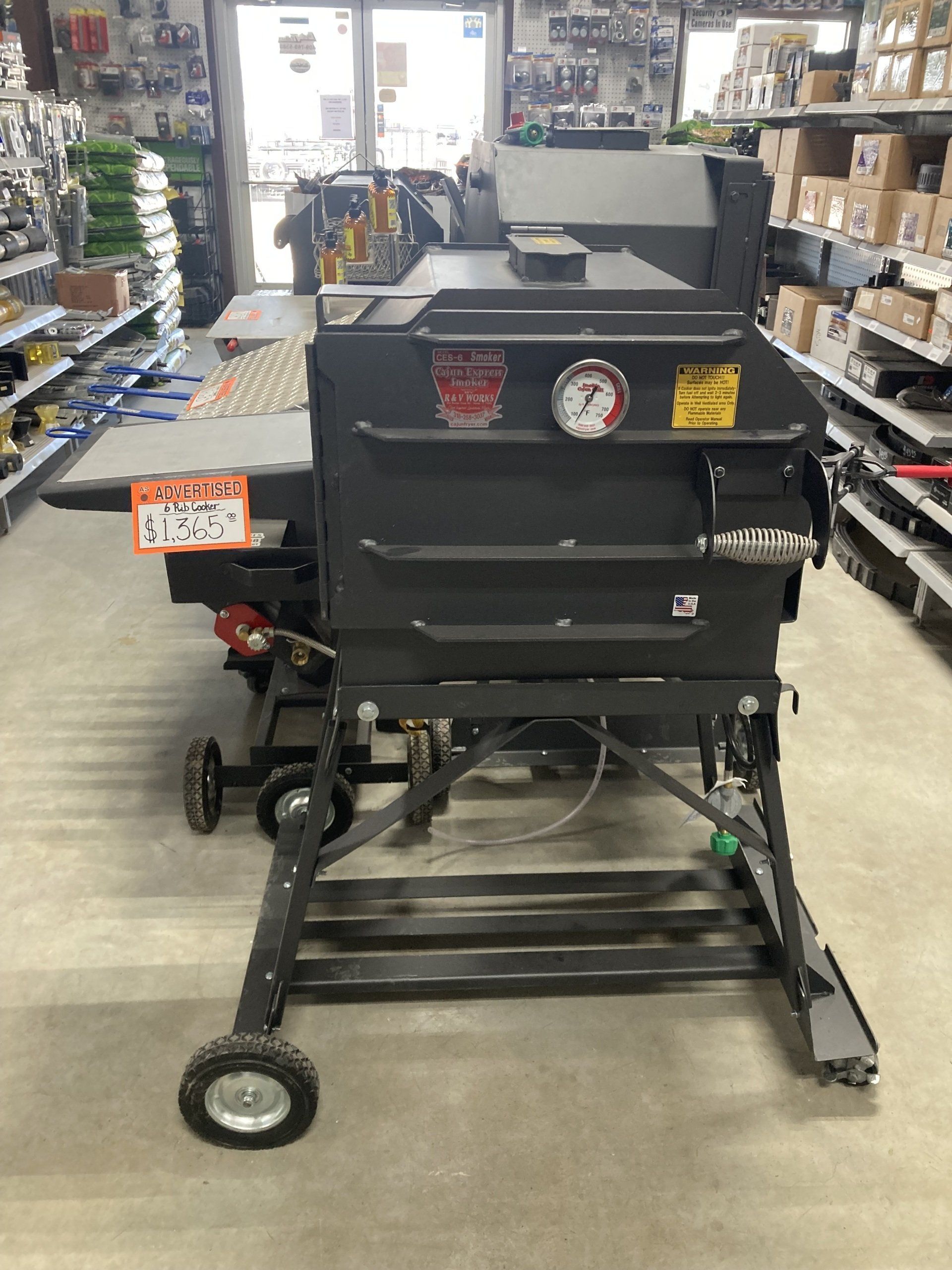 A large black oven is sitting on a cart in a store.