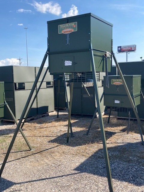 A green deer feeder is sitting on top of a pile of gravel.