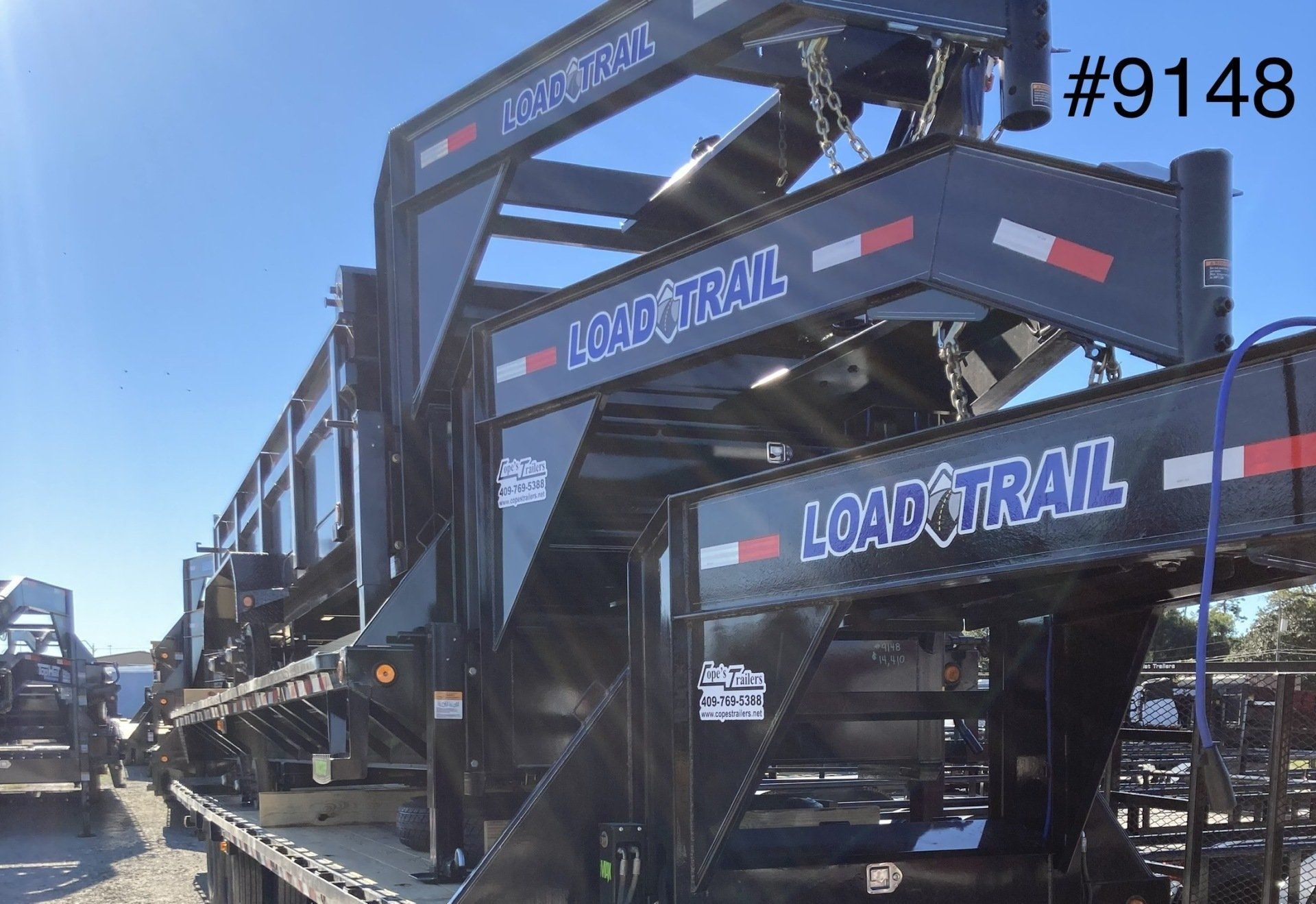 A load trail trailer is parked on the side of the road.