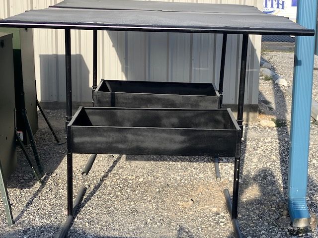A metal table with three drawers on it is sitting on the ground in front of a building.