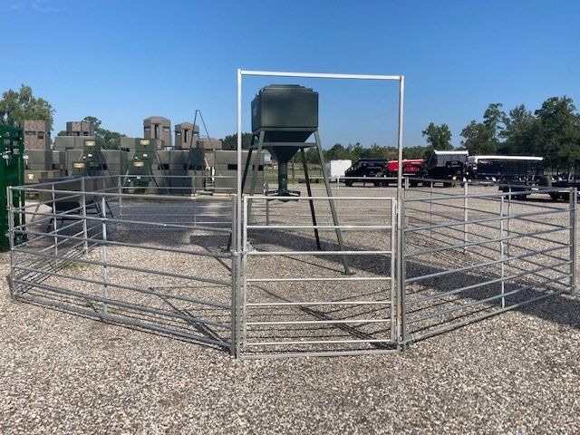 A metal fence with a gate and a feeder in the background
