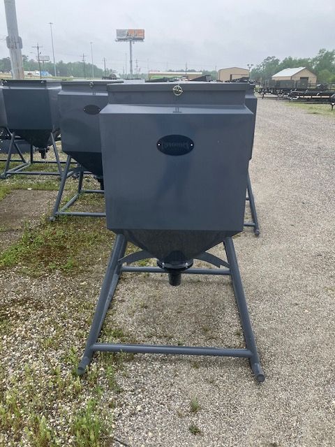 A row of feeders are lined up in a gravel lot.