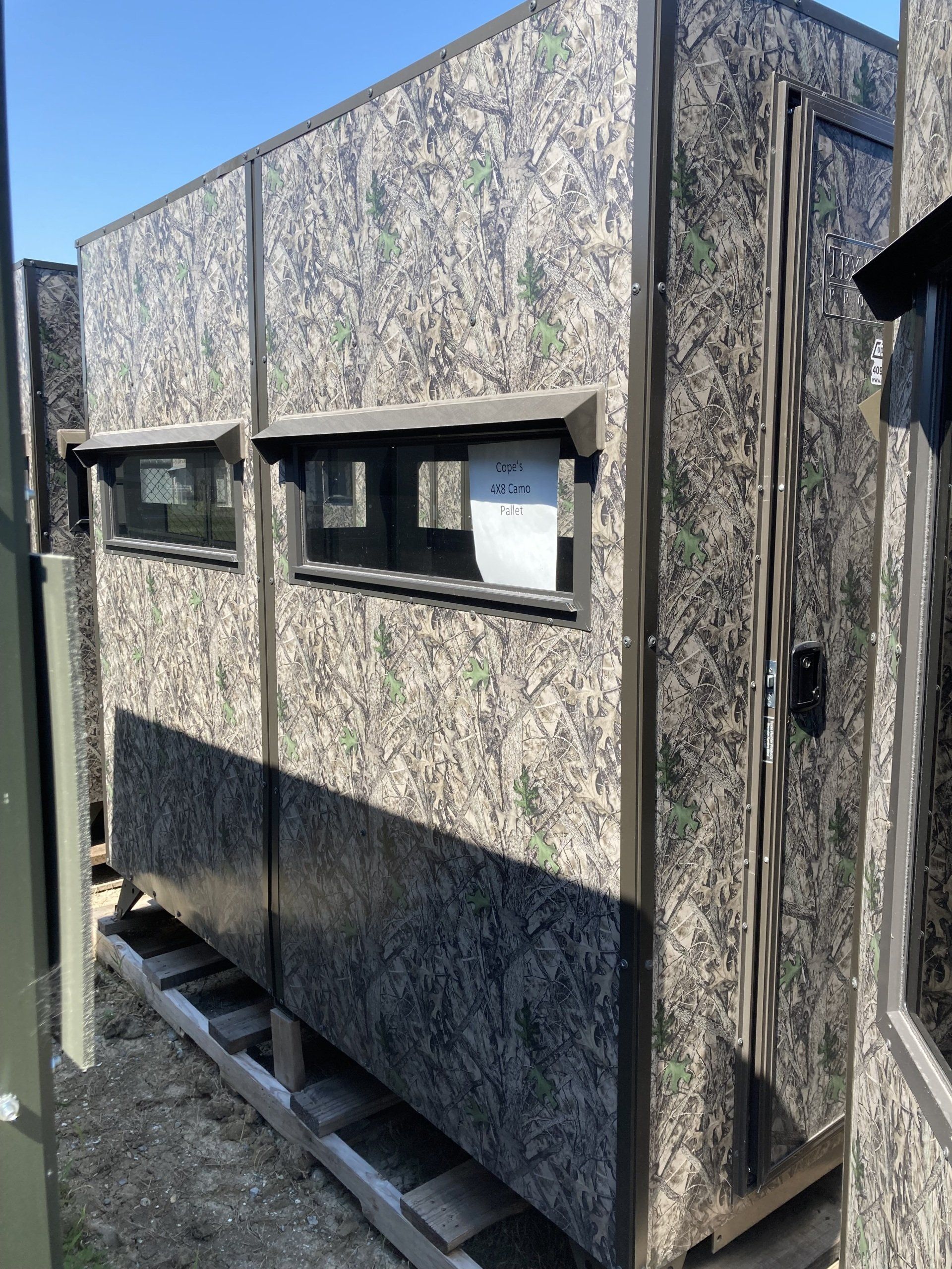 A building with a camouflage pattern on it is sitting on a wooden pallet.
