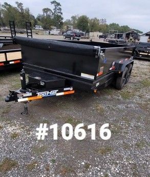 Black dump trailer with orange and white accents, in a lot with other trailers, with
