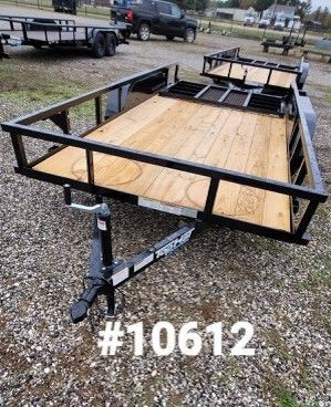 Black trailer with wooden bed, surrounded by black metal frame, on gravel. 