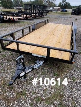 Black utility trailer with wooden deck, on gravel. 